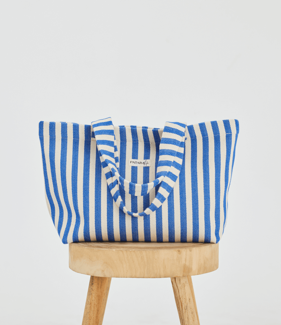 a blue and white striped tote bag placed up right on a stool