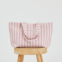  a light pink and white striped tote bag placed up right on a stool