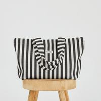  a black and white striped tote bag placed up right on a stool