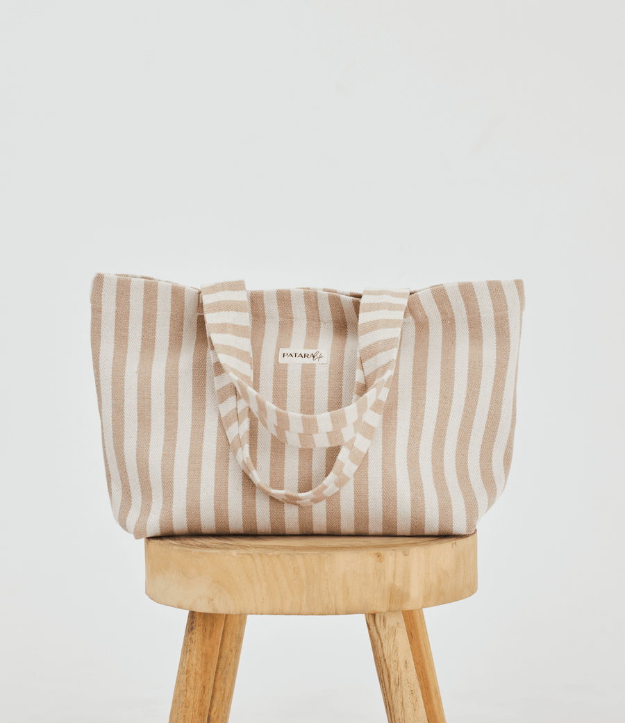  a light brown and white striped tote bag placed up right on a stool